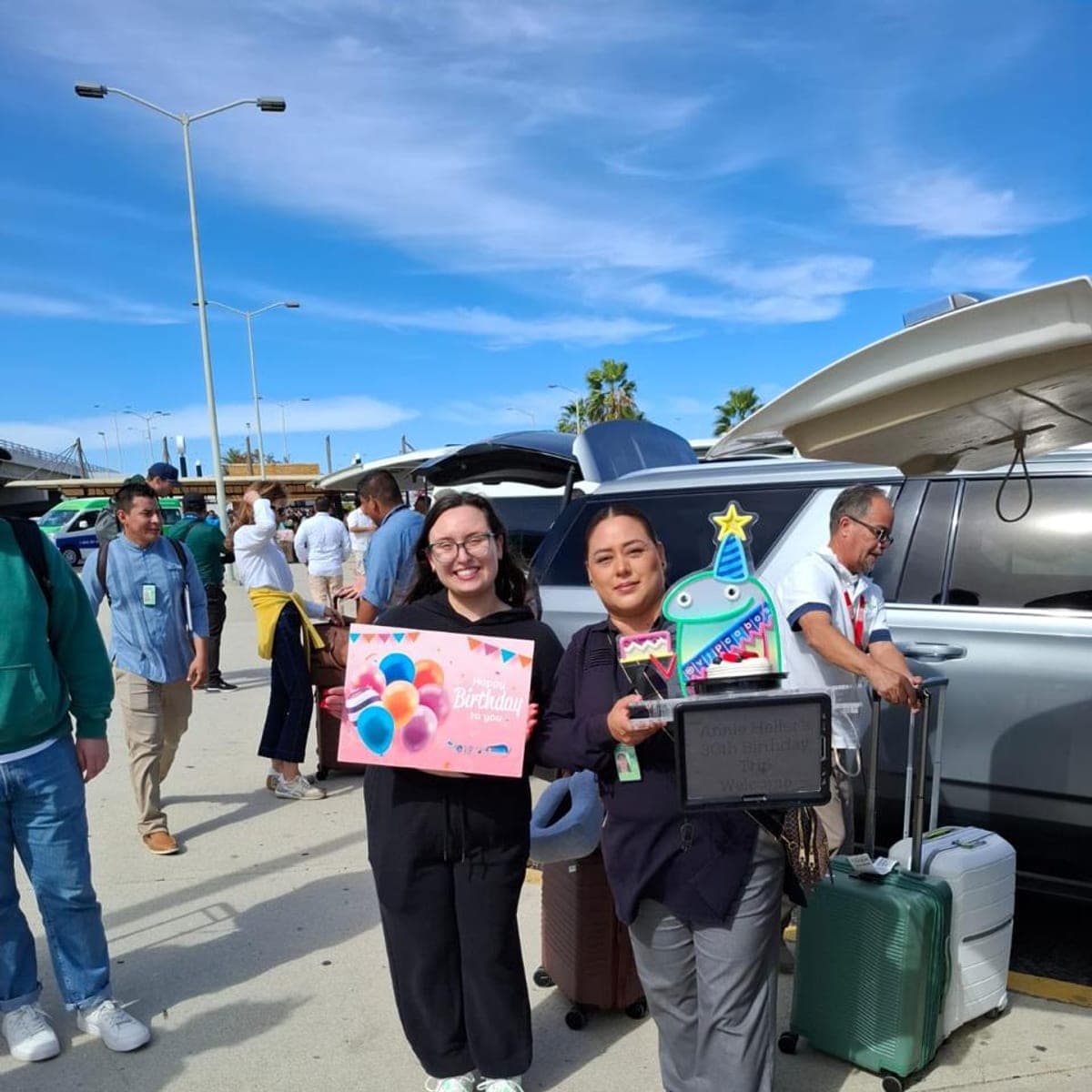 Host welcoming a guest with a birthday sign and cake at SJD